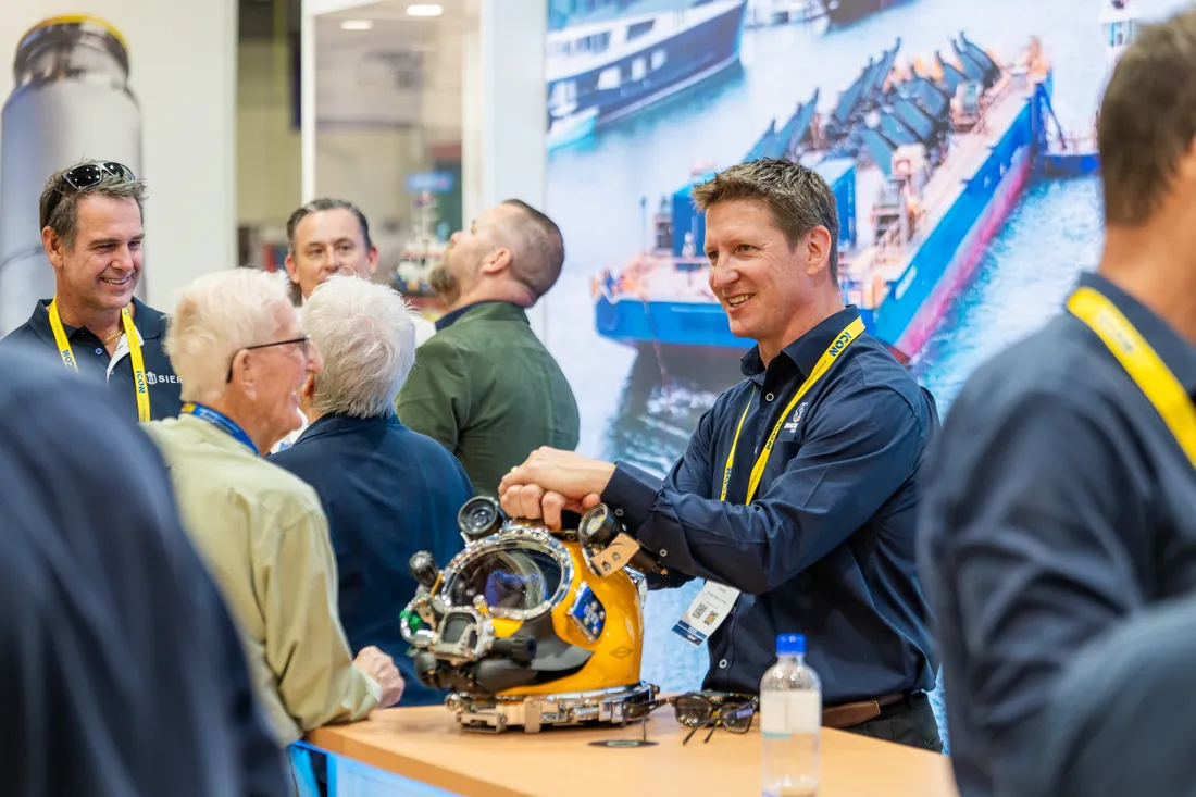 Visitors at an exhibitor stand looking at a product demonstration